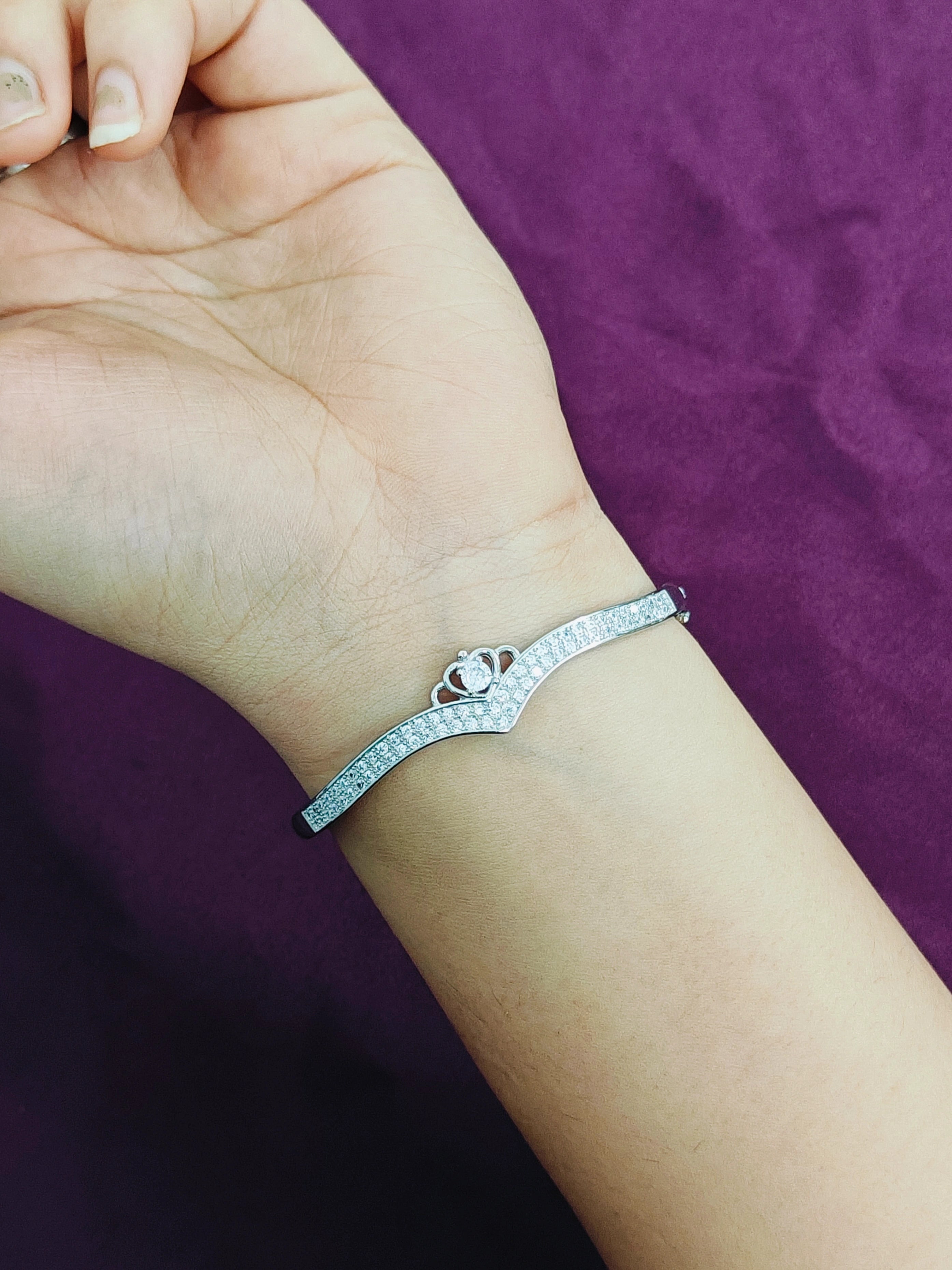 Silver bracelet on a wrist with a purple background